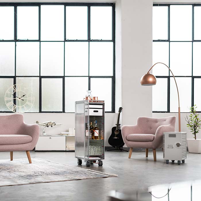 Offener Raum im Industrial Style mit verschiedenen Möbeln wie Couches, einer Lampe, einem Glastisch sowie einer großen Fensterfront
